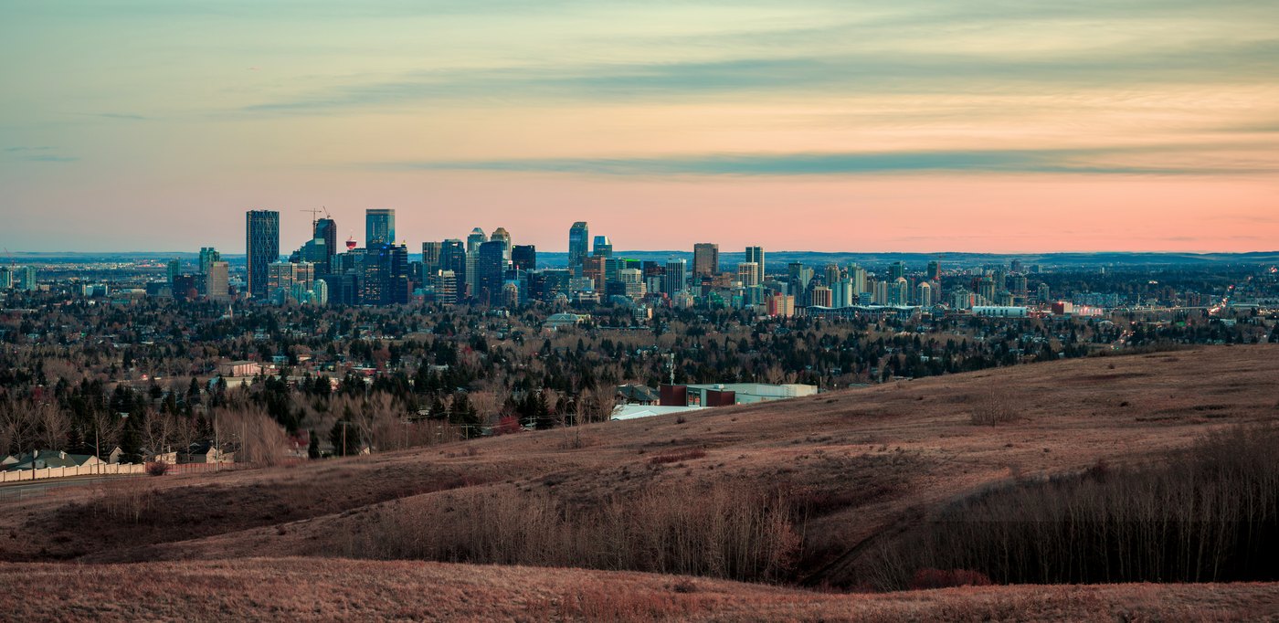 The downtown Calgary skyline at sunset, seen across the grassland of Nose Hill Park